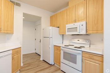 A kitchen with white appliances and wooden cabinets.